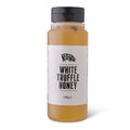 A clear plastic bottle of Truffle Pig White Truffle Honey with a black cap and a white label, set against a plain white background.