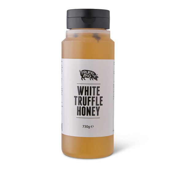 A clear plastic bottle of Truffle Pig White Truffle Honey with a black cap and a white label, set against a plain white background.