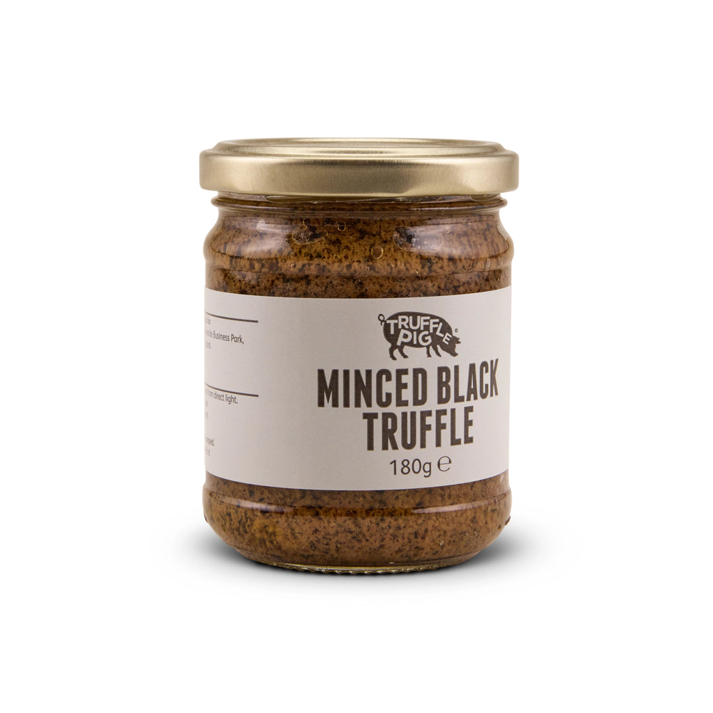 A glass jar of Truffle Pig's Minced Black Truffle 180g with a gold lid and a beige label, set against a plain white background.