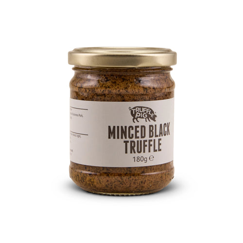 A glass jar of Truffle Pig's Minced Black Truffle 180g with a gold lid and a beige label, set against a plain white background.